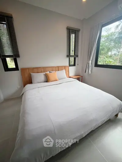 Modern bedroom with large windows and minimalist decor, offering a serene and airy ambiance.