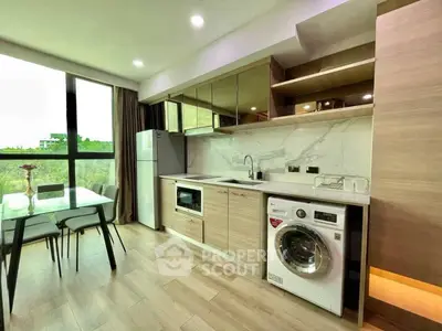 Modern kitchen with washing machine and dining area, featuring sleek cabinets and large window view.