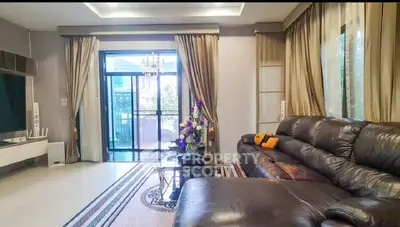 Luxurious living room with leather sofa and elegant curtains, featuring a view of the balcony.