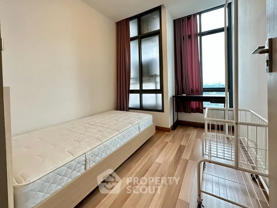 Modern bedroom with large windows and minimalist design in a high-rise apartment.