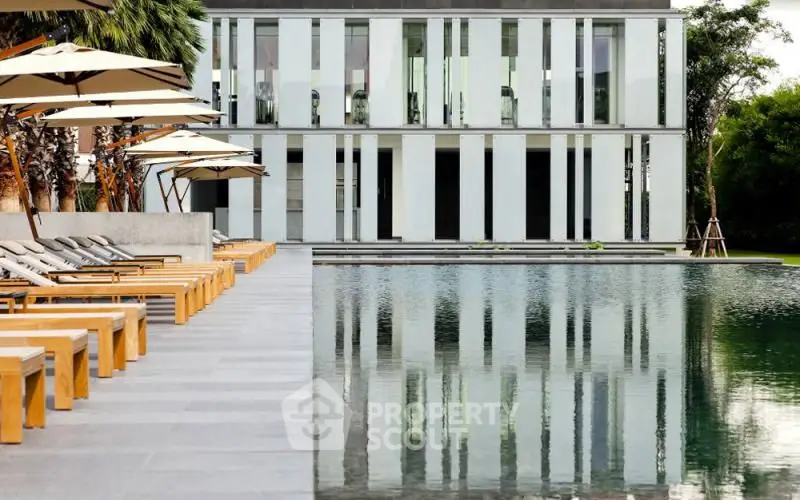 Luxurious modern building with serene poolside and elegant loungers, perfect for relaxation and leisure.