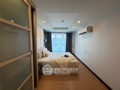 Spacious modern bedroom with cozy bed and stylish decor in a well-lit apartment.