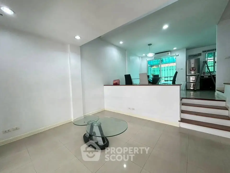 Spacious modern living room with sleek glass table and elevated dining area, perfect for stylish urban living.