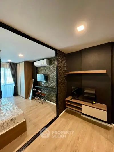 Modern bedroom with stylish decor and wooden flooring, featuring a cozy bed and a sleek entertainment unit.