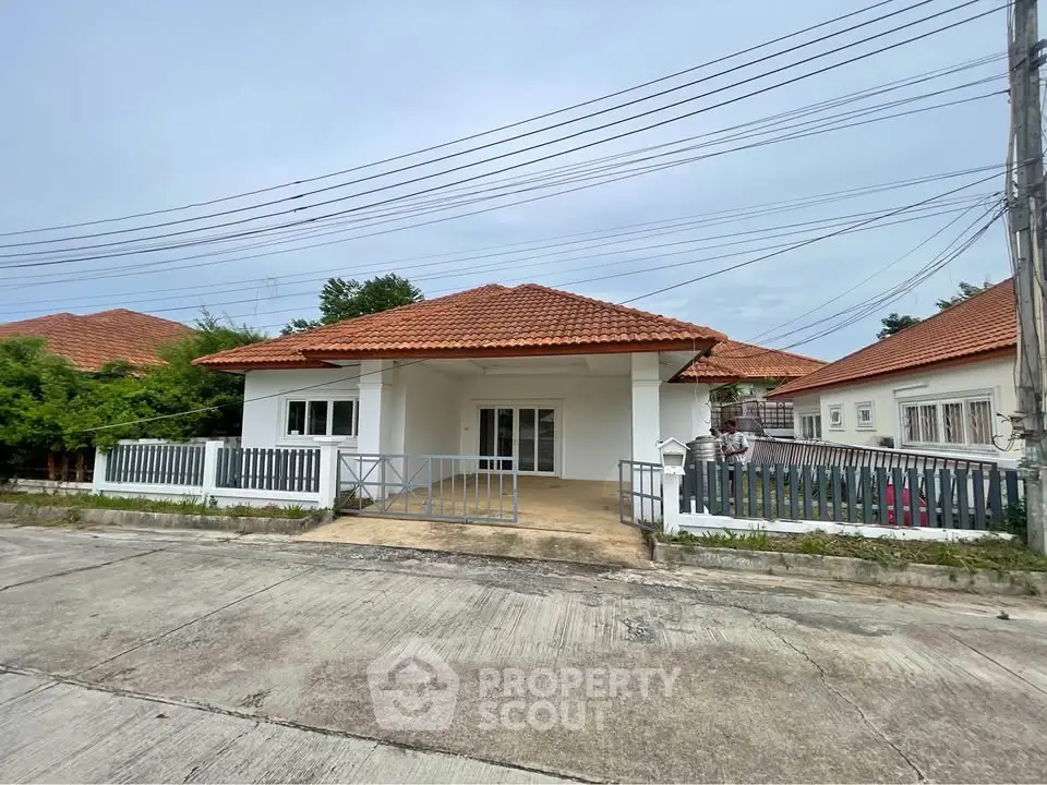 Charming single-story house with red-tiled roof and spacious front yard in a serene neighborhood.