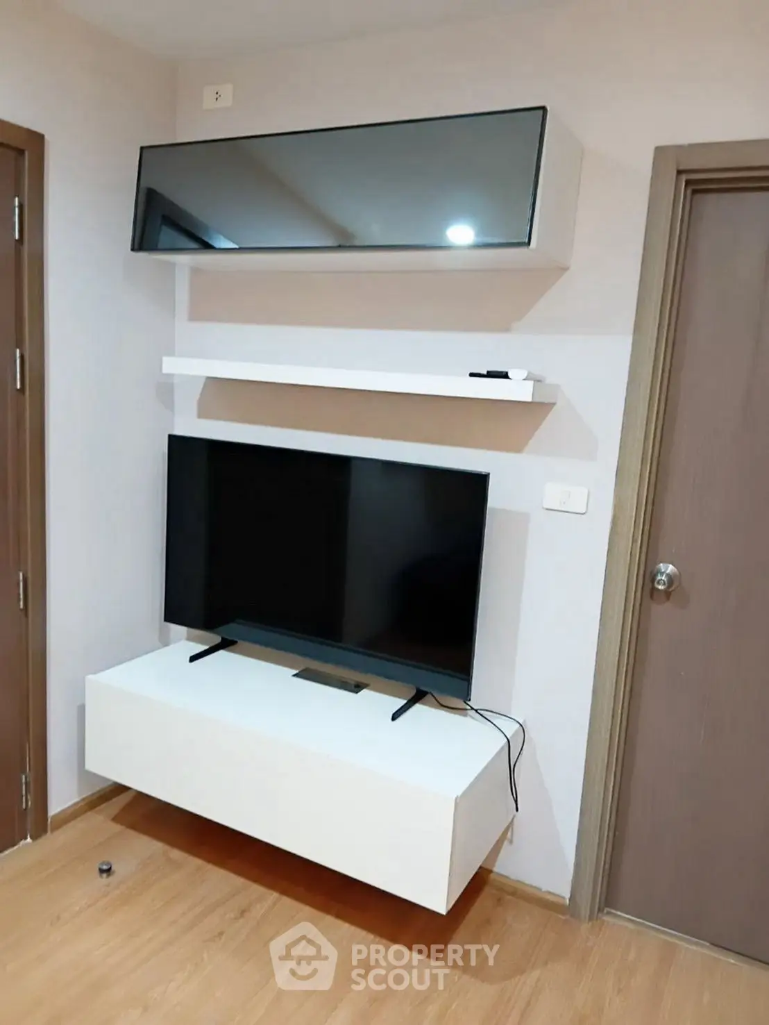 Modern living room with sleek TV setup and wooden flooring