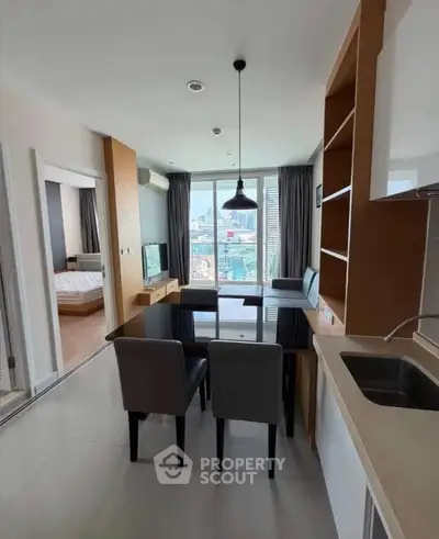 Modern open-plan living room with dining area and city view, featuring sleek furniture and natural light.