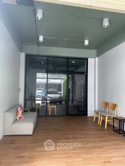 Spacious modern interior with wooden flooring and glass doors, ideal for versatile living or office space.