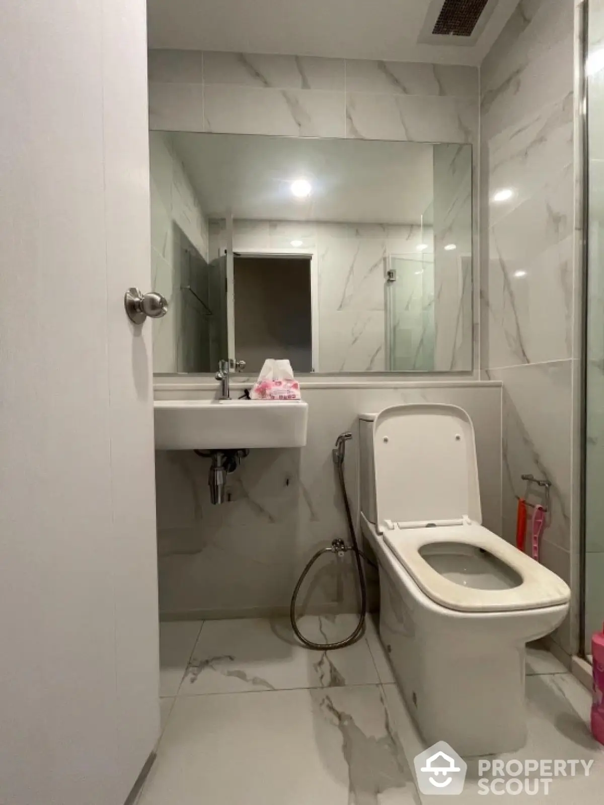 Modern bathroom with sleek design and marble tiles, featuring a contemporary toilet and sink.