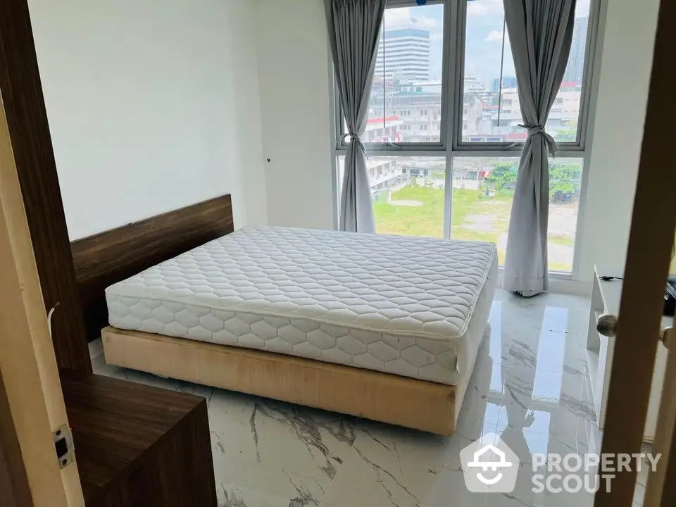 Spacious bedroom with large windows and city view, featuring modern design and natural light.