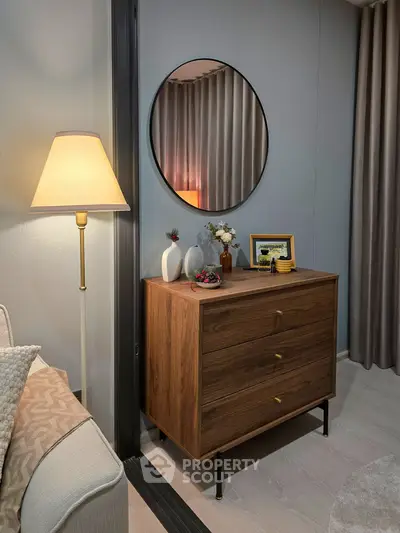 Stylish living room corner with elegant lamp, wooden dresser, and decorative mirror.