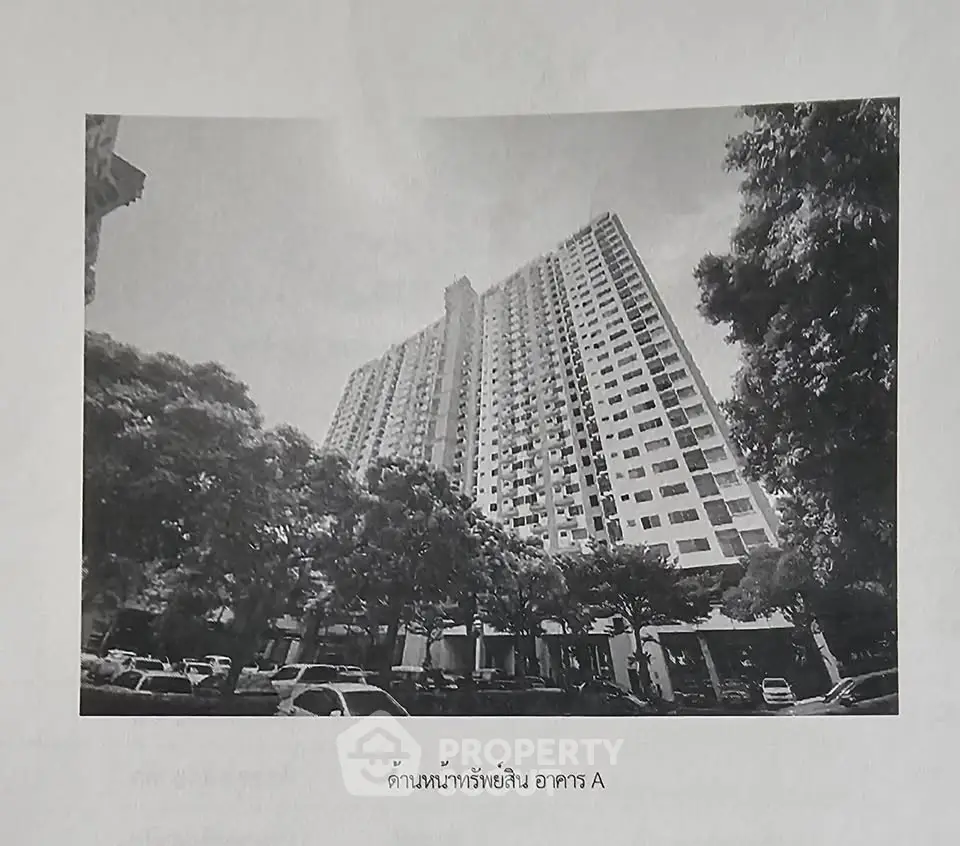 High-rise residential building with lush greenery and ample parking space.