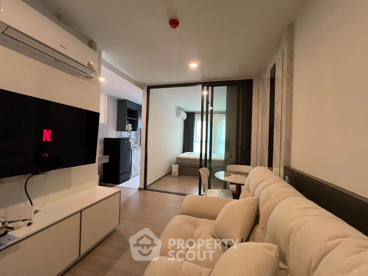 Modern living room with cozy sofa and open view to bedroom