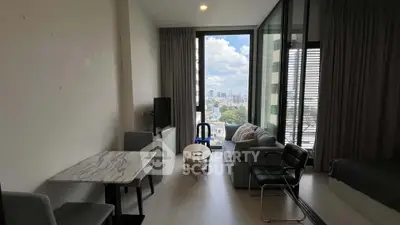 Modern living room with city view, featuring sleek furniture and large windows.