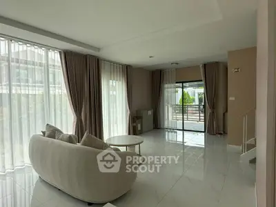 Spacious living room with elegant curtains and modern furniture, offering a bright and airy ambiance.