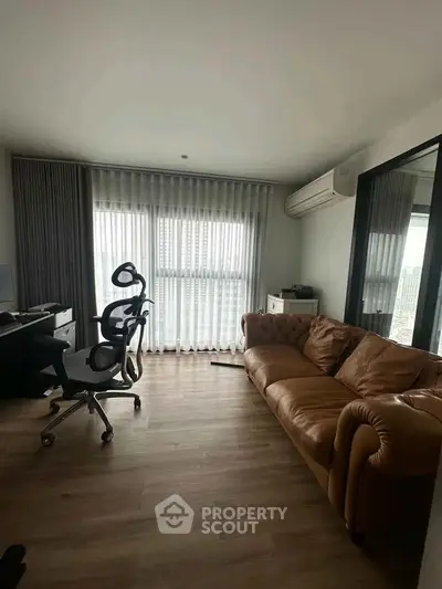 Modern living room with leather sofa and ergonomic chairs, featuring floor-to-ceiling windows.