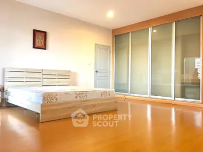 Spacious bedroom with wooden flooring and large sliding closet doors.