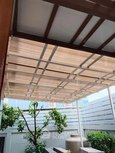 Charming outdoor patio with modern pergola and lush greenery, perfect for relaxation and entertaining.