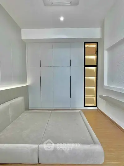 Modern minimalist bedroom with sleek built-in storage and cozy bed.