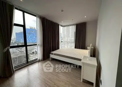 Spacious bedroom with large windows offering city views and modern furnishings.