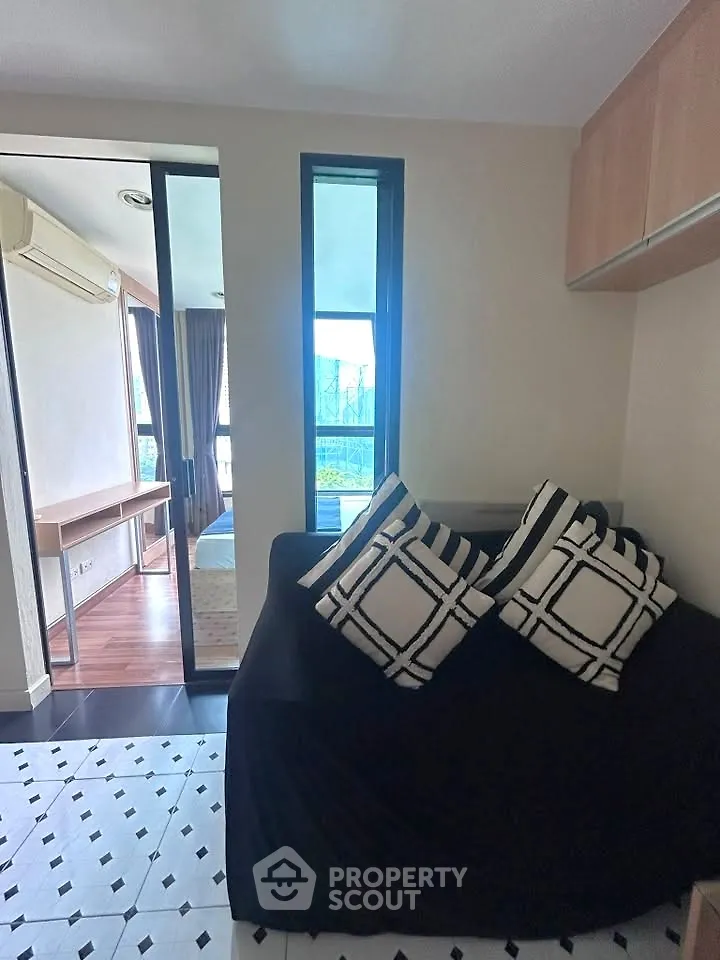 Cozy living room with stylish decor and natural light, leading to a bedroom with a scenic view.