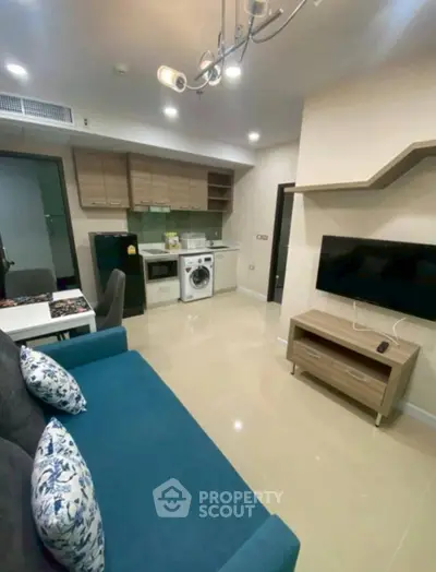 Modern living room with open kitchen, featuring a washing machine and stylish decor.