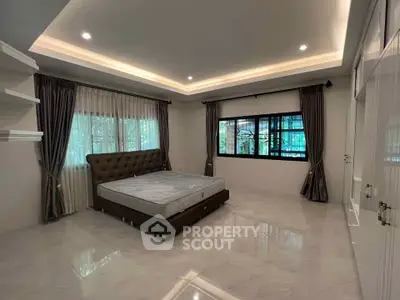 Spacious bedroom with elegant lighting and large windows for natural light.