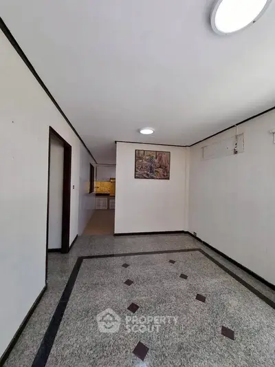Spacious interior with elegant flooring and a glimpse of the kitchen area, perfect for modern living.