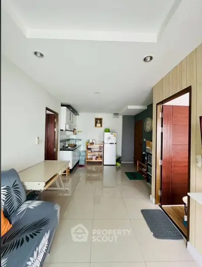 Modern open-layout living room with kitchen, featuring sleek design and natural light.