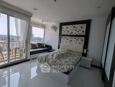 Spacious bedroom with city view and balcony access, featuring modern decor and ample natural light.