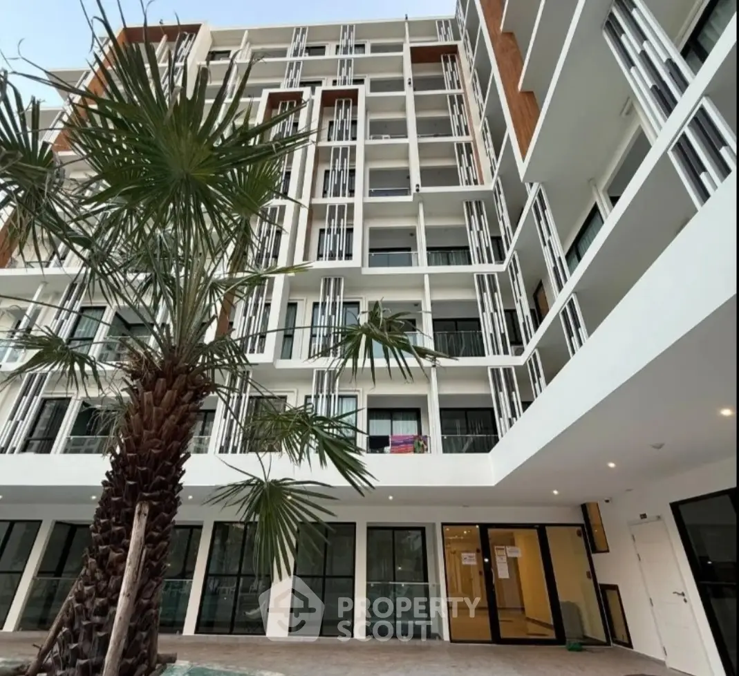 Modern apartment building exterior with palm trees and large windows, showcasing contemporary architectural design.