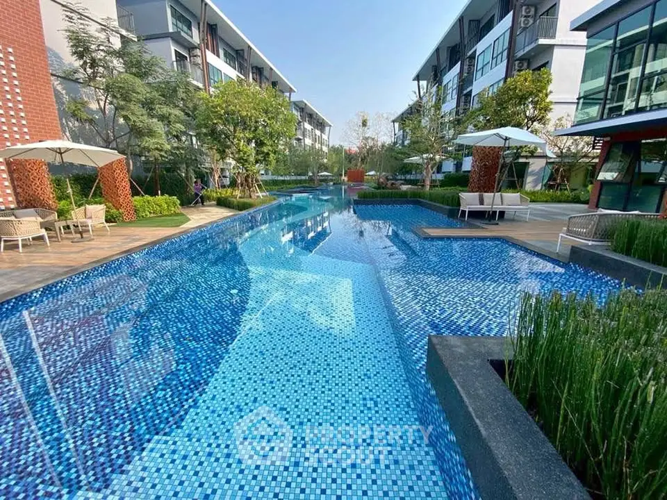 Luxurious modern apartment complex with stunning outdoor pool and lush greenery.