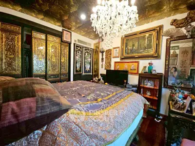 Luxurious bedroom with ornate decor and chandelier in elegant home.