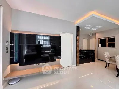 Modern living room with sleek TV setup and elegant dining area, featuring contemporary design and ambient lighting.