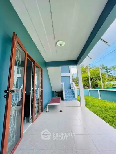 Charming covered patio with modern design and lush green surroundings.