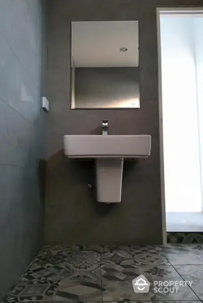 Sleek modern bathroom with stylish gray tiles and designer sink, complemented by a large mirror, exuding contemporary elegance.