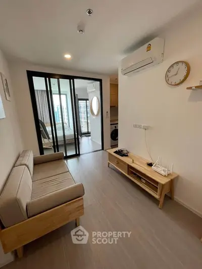 Modern living room with wooden furniture and sliding glass doors leading to a bedroom.