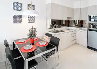 Modern kitchen with dining area, sleek cabinetry, and festive decor in a stylish apartment.