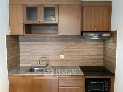 Modern kitchen with wooden cabinets and sleek appliances in a cozy apartment.
