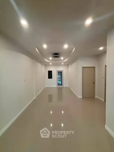 Spacious empty room with glossy tiled floor and modern ceiling lights