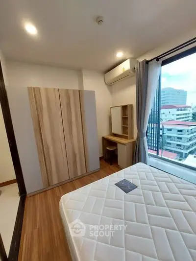 Modern bedroom with city view, featuring a stylish wardrobe and comfortable bed.
