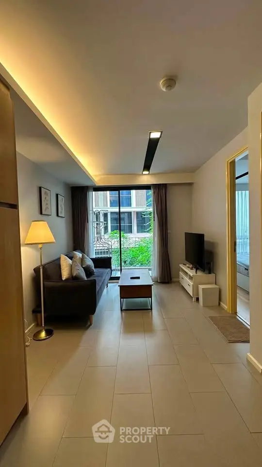 Modern living room with cozy sofa, stylish lighting, and large window view in a contemporary apartment.