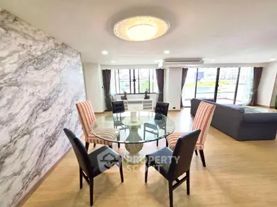 Spacious living room with elegant dining area and large windows offering natural light.