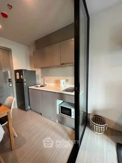 Modern compact kitchen with sleek cabinetry and appliances in a stylish apartment.
