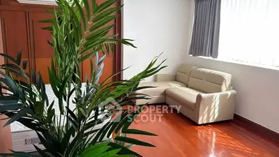 Spacious living room with elegant wooden flooring and cozy beige sofa, perfect for relaxation.