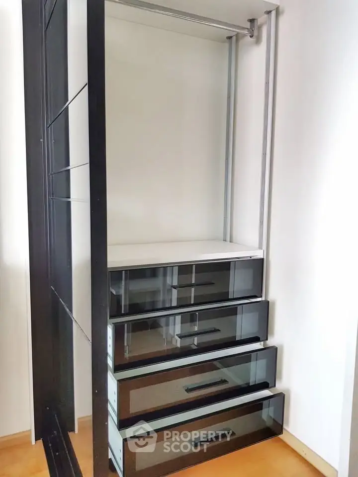Spacious modern wardrobe with sleek black drawers and ample storage space.
