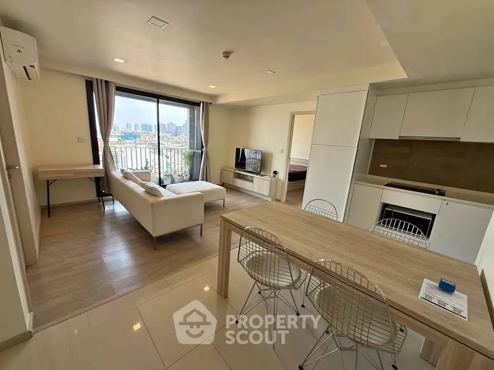 Modern open-plan living room with city view, featuring sleek furniture and contemporary kitchen design.