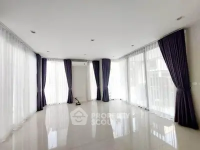 Spacious living room with large windows and elegant curtains, perfect for natural light lovers.
