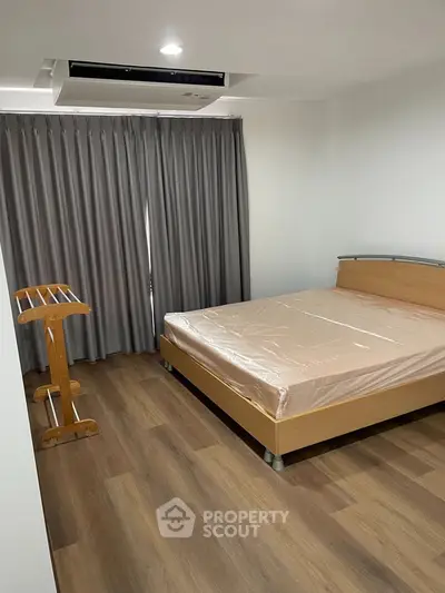 Spacious bedroom with wooden flooring and modern furnishings in a stylish apartment.