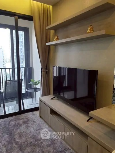 Modern living room with balcony view, featuring sleek TV setup and stylish decor in urban apartment.